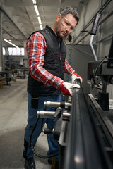 Fototapeta na wymiar Adult male inspecting product before working at machine