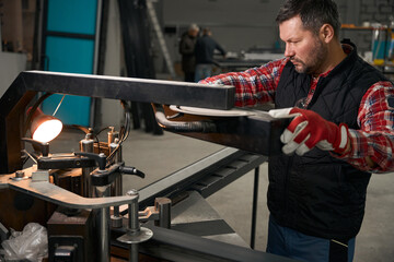 Adult male preparing machine for working in the workshop