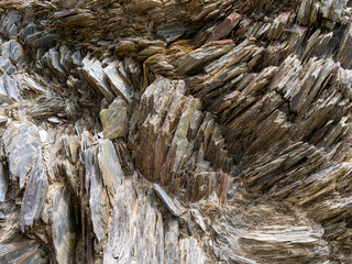 Stone close-up, stone background. Compressed rock layers formation in various colors and thicknesses, Nature and Geological science concept. The close-up relief of the rocks layers.