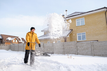 Man removing snow from sidewalk after snowfall. Portrait of man with dog during winter time