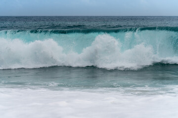 Clear blue sea wave crashing on a cloudy day. Climate nature concept. Front view of a stormy sea.