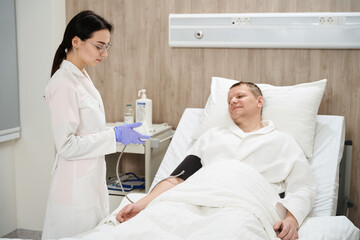 Elegant nurse is monitoring blood pressure in the clinic