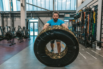 Obraz na płótnie Canvas Athlete rolling a training wheel and looking serious