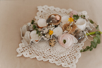 easter table decoration with flowers and candles in egg shells on white openwork napkin on beige tablecloth