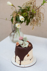 Easter cottage cheese cake with chocolate icing and meringue figures on the top standing on the table with white table cloth on the background