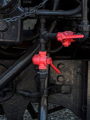 two red corner cranes on the black-painted pipes of an old steam locomotive - shut-off valves