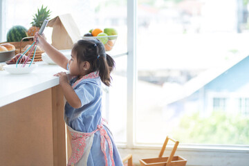 Cute little girl enjoys cooking in the kitchen, pretend to be a chef