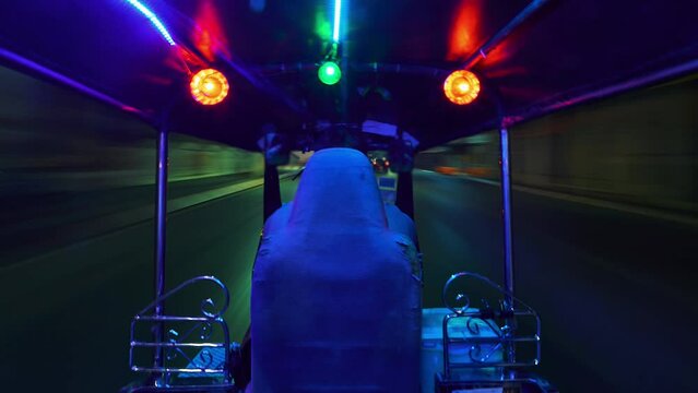 Point of view: riding thai tuk-tuk taxi around night streets of Chiang Mai, Thailand. Wide angle 4K timelapse hyperlapse popular tourist transportation in Asia. Driver face, logotypes are blurred.
