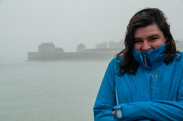 A woman stands at the mouth of the Niagara River on Lake Ontario during a foggy and rainy day