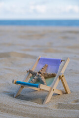 Sunny holidays on the beach with sand beach accessories with sea shells and sea star. Sun lounger stand sea Ocean background. Wooden beach chairs. Summer holiday vacation concept. 