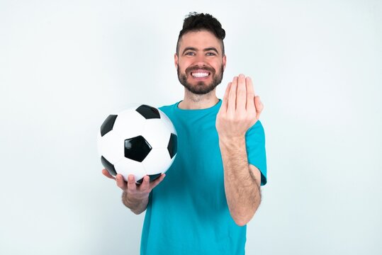 Young man holding a ball over white background inviting to come with hand. Happy that you came