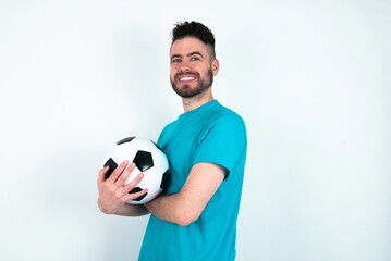 Young man holding a ball over white background happy face smiling with crossed arms looking at the camera. Positive person.