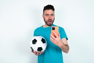 Focused Young man holding a ball over white background use smartphone reading social media news, or important e-mail