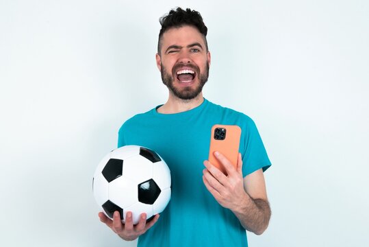 Young man holding a ball over white background taking a selfie  celebrating success