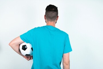 The back view of a Young man holding a ball over white background . Studio Shoot.