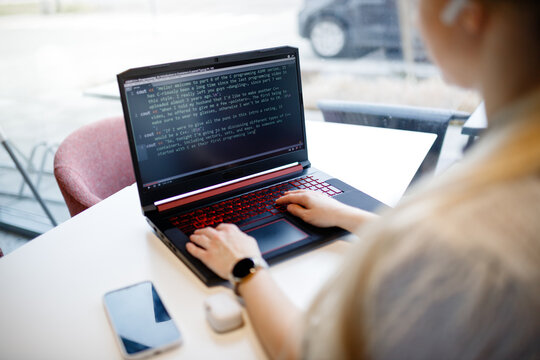 The girl programs on the computer over a cup of coffee