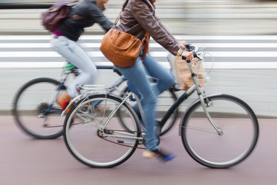 women riding bicycle on a city street in motion blur