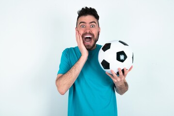 Young man holding a ball over white background Pleasant looking cheerful, Happy reaction