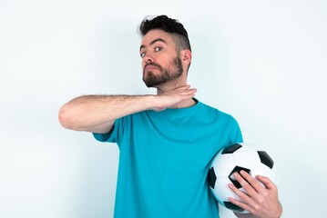 Young man holding a ball over white background cutting throat with hand as knife, threaten...