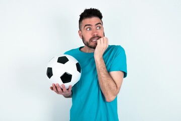 Terrified Young man holding a ball over white background looks empty space home alone moonless night