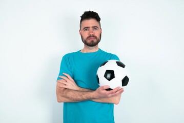 Confident Young man holding a ball over white background with arms crossed looking to the camera