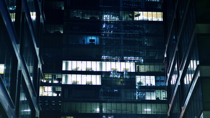 Pattern of office buildings windows illuminated at night. Glass architecture ,corporate building at night - business concept. Blue graphic filter.