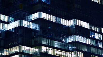 Obraz premium Pattern of office buildings windows illuminated at night. Glass architecture ,corporate building at night - business concept. Blue graphic filter.