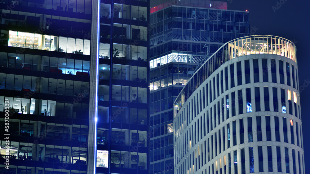 Poster Pattern of office buildings windows illuminated at night. Glass architecture ,corporate building at night - business concept. Blue graphic filter.