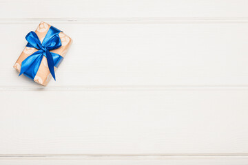 Gift box with a blue satin bow on a white wooden background.