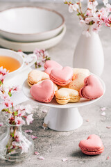 Obraz na płótnie Canvas Macarons or French macaroons in heart shapes with cherry blossom branch for Mothers Day