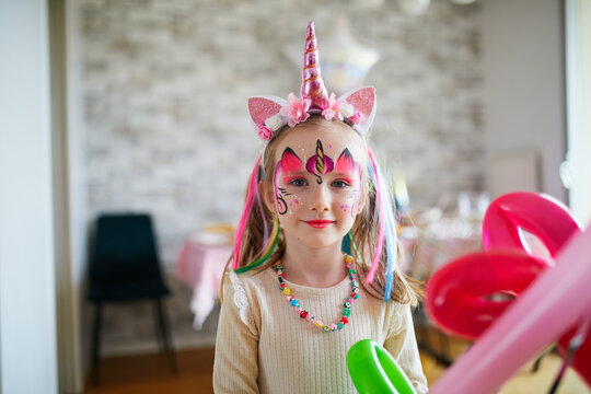 Little preschooler girl in unicorn costume with facepaint on a birthday party