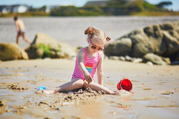 Preschooler girl playing on the sand beach at Atlantic coast of Normandy, France