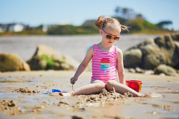 Preschooler girl playing on the sand beach at Atlantic coast of Normandy, France