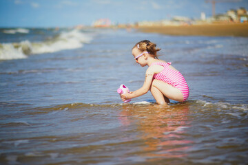 Preschooler girl playing on the sand beach at Atlantic coast of Normandy, France