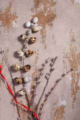 Table Easter decor set with quail eggs, red ribbon and willow branches on wooden vintage table.