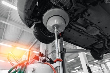 Change motor oil in auto service garage. Car is on lift, lubricant is drained into special tray