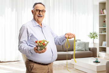 Mature man holding a salad and a measuring tape in a living room