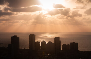 Sunset above Tel Aviv. Sunrays on the sea surface and high-rises