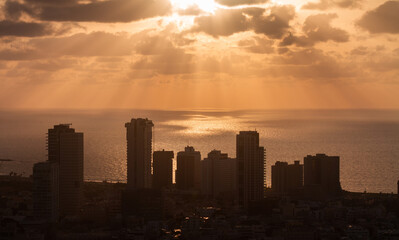 Sunset above Tel Aviv panorama. Sunrays on the sea surface and high-rises