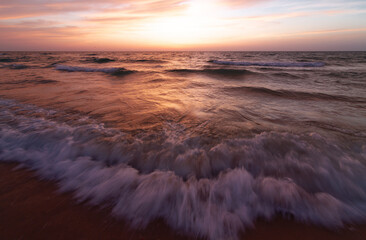 Sea sandy beach during the sunset, waves