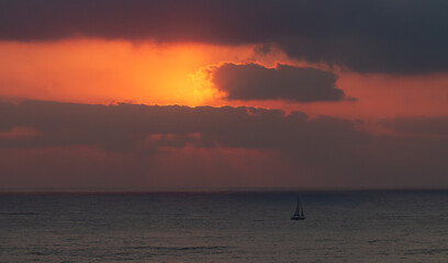 Seascape: Sailboat goes on the waves during sunset