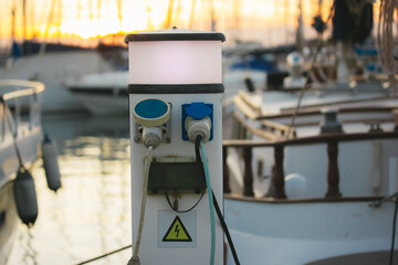 Charging station with electrical outlets for yachts in a harbor. Power socket bollard on pier....