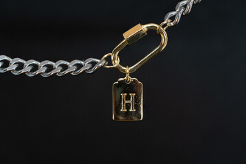Gold chain jewelry with a gold earring and the letter H macro photography