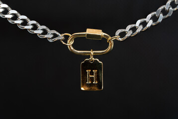 Fototapeta na wymiar Gold chain jewelry with a gold earring and the letter H macro photography