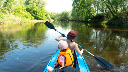 Family kayak trip. Mom and daughter rowing a boat on the river, a water hike, a summer adventure. Eco-friendly and extreme tourism, active and healthy lifestyle