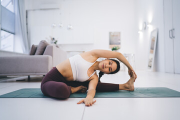 Fototapeta na wymiar Slim woman doing revolved head to knee yoga in pose