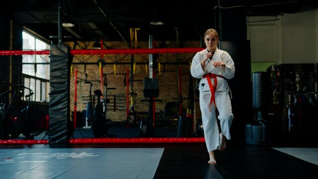A girl practices karate in a gym A woman in kimono practices movements and poses Martial arts