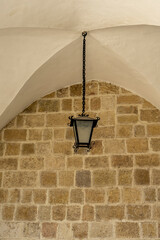 Outdoor antique pendant lamp hanging from the cross vault with stone wall on the background in St. Paul's Church in Antakya, Hatay. Copy space for text.