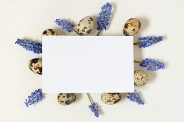 Easter composition with paper blank quail eggs and fresh flowers.Top view, flat lay, copy space.
