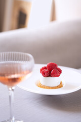 Elegant set table with raspberry dessert and a glass of champagne. Trendy interior background.